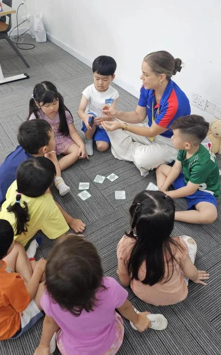 Teacher and young campers playing a card game, 2025